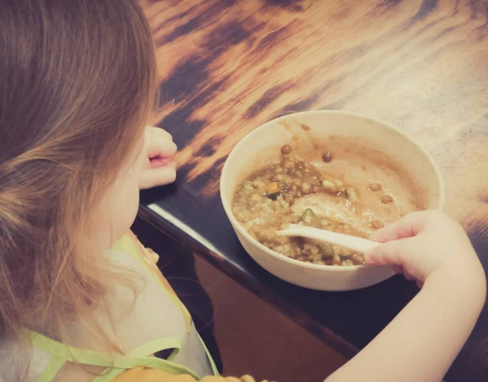 Una niña comiendo un plato de lentejas. Guardería en Chamberí (Madrid)